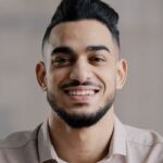 happy joyful guy hispanic arabian handsome young man casual model with toothy smile look at camera optimistic male face portrait smiling businessman intelligent millennial posing indoors close up view